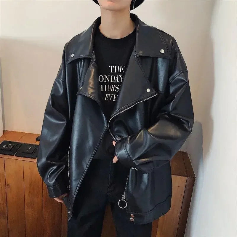 Person wearing a black leather jacket over a black t-shirt with text, standing against a neutral background.